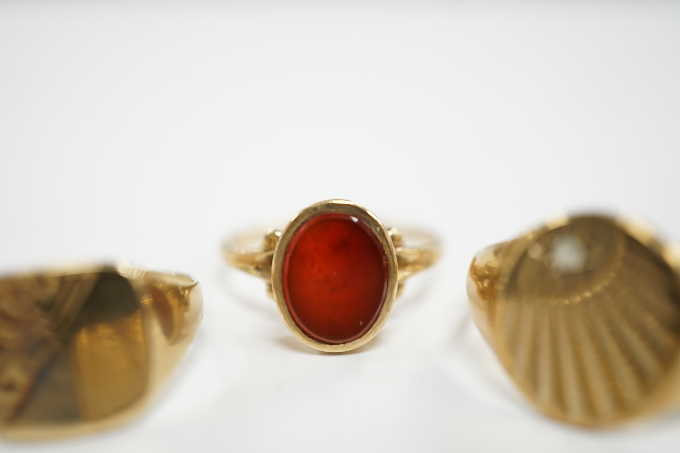 Four assorted 9ct gold rings including a wedding band and carnelian set, gross weight 13.6 grams.